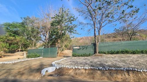 a fence in front of a field with a tree at Glamping en Playa Potrero in Potrero