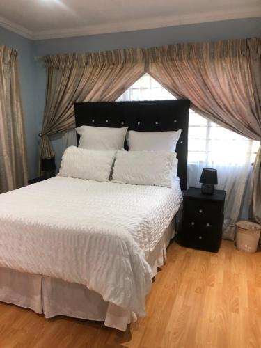 a bedroom with a large bed with white sheets and a window at JB Countrylife Accommodation in Centurion