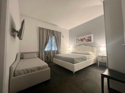 a bedroom with two beds and a chair and a window at Acquamarina Luxury Rooms in Budoni