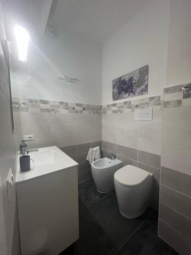 a white bathroom with a toilet and a sink at Acquamarina Luxury Rooms in Budoni