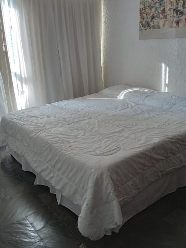 a white bed in a bedroom with a window at Torre del Plata II in Punta del Este