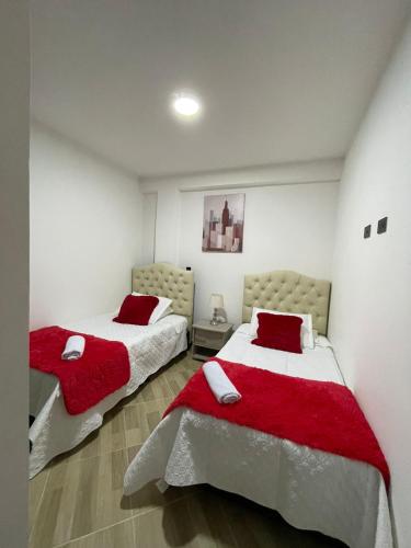 2 camas en una habitación blanca con almohadas rojas en Moderno apto familiar piso 2 en Santa Rosa de Cabal