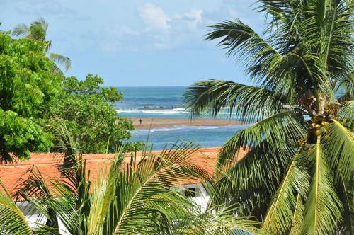 a view of a beach with a palm tree and the ocean at Hotel Bay Watch Unawatuna in Unawatuna
