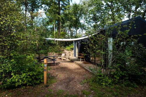 una cabina nel bosco con tavolo da picnic e tenda di Vague Luxurious Tiny House Luxe Wellness, Spa Bad,Beamer, Veluwe a Nunspeet