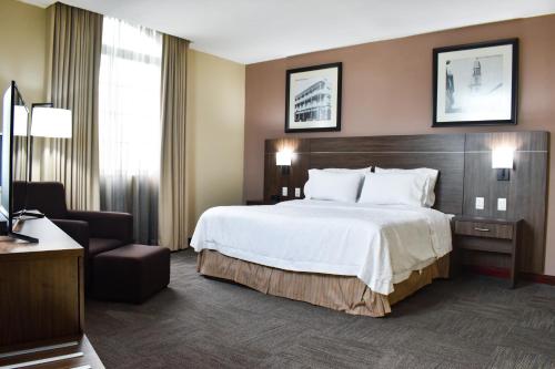 um quarto de hotel com uma cama grande e uma cadeira em Hampton Inn Tampico Zona Dorada em Tampico