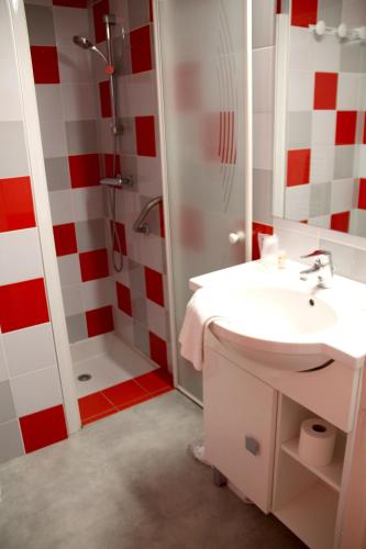 La salle de bains rouge et blanche est pourvue d'un lavabo et d'une douche. dans l'établissement VVF Collonges-la-Rouge, à Collonges