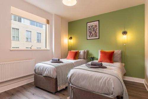 two beds in a room with green walls and a window at Stunning Brand New One Bed City Apartment in Leicester