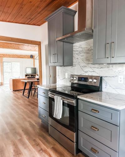 a kitchen with gray cabinets and a stove top oven at Lakeside Cabin - Serene Retreat with Lake Monroe Views and Wraparound Deck in Brown County in Nashville