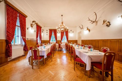 a dining room with tables and chairs and a chandelier at Zámeček Waldsteinovo Zátiší in Svatoslav