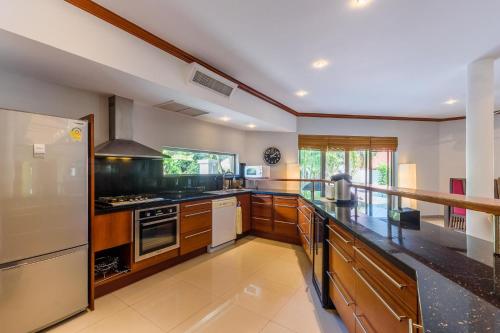 a large kitchen with wooden cabinets and stainless steel appliances at Amber Pool Villa Your private slice of paradise in Rawai Beach