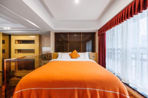 an orange bed in a room with a large window at Argyle WAIFIDEN Baolidian Hotel -Free shuttle bus during Canton Fair in Guangzhou
