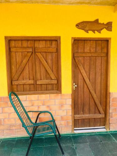 a green chair sitting in front of a building with two doors at Pousada Segredo in Bonito