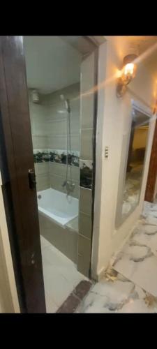 uma casa de banho com um chuveiro e uma banheira em شقة مفروشة ميامي em Alexandria