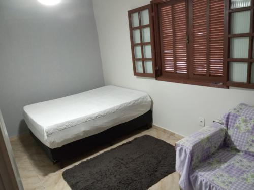 um pequeno quarto com uma cama e um sofá em housecabofrio em Cabo Frio