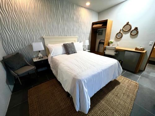 1 dormitorio con 1 cama blanca y 1 silla en Villas Quijote Valle de Guadalupe en Bonito