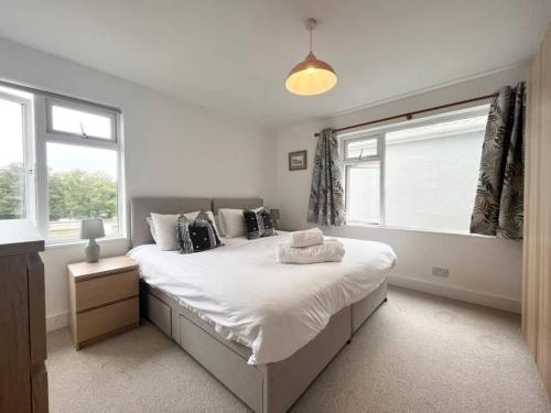 a bedroom with a large white bed with windows at Bright Bungalow with 3 bedrooms and Garden in Porthlevan in Porthleven