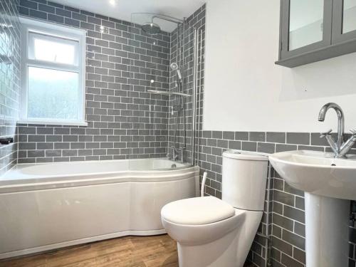 a bathroom with a toilet and a sink and a tub at Bright Bungalow with 3 bedrooms and Garden in Porthlevan in Porthleven