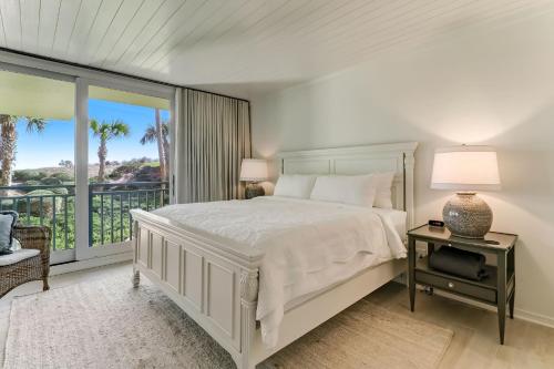 a white bedroom with a bed and a balcony at 1380 Shipwatch in Amelia Island