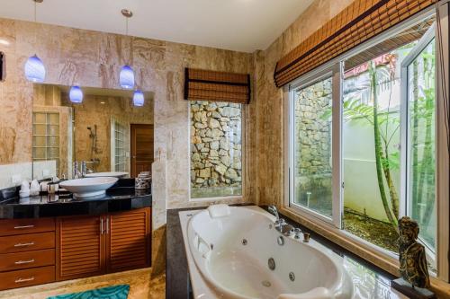 Un baño con bañera, lavabo y ventana. en Aster Pool Villa, en Rawai Beach