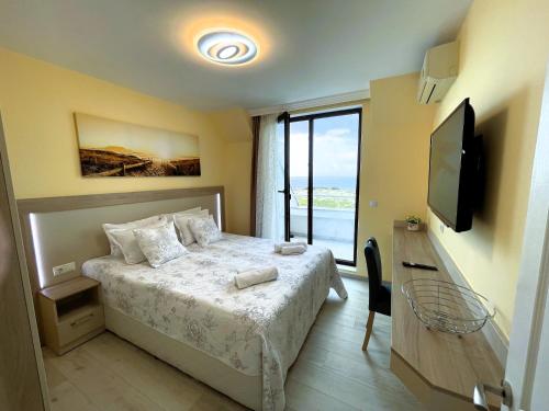 a bedroom with a bed and a tv and a window at Apart-Hotel Panorama Sea LUX in Primorsko