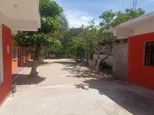 une allée vide entre deux bâtiments arborés dans l'établissement cuartos en renta El portón azul, à Ixtepec