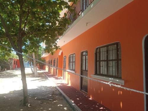 un bâtiment orange avec un arbre à côté dans l'établissement cuartos en renta El portón azul, à Ixtepec