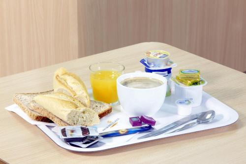 a breakfast tray with bread and toast and a glass of orange juice at Premiere Classe Beziers in Béziers