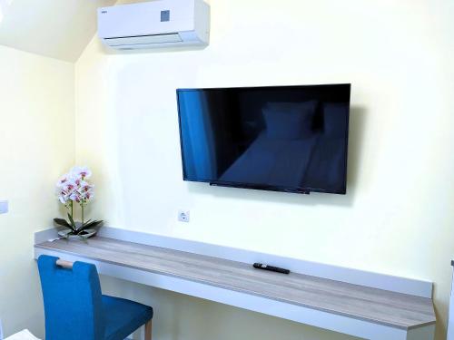 a flat screen tv on a wall with a blue chair at Apart-Hotel Panorama Sea LUX in Primorsko