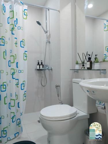 ein weißes Bad mit einem WC und einem Duschvorhang in der Unterkunft Azure Blue Cozy Unit with PS4 & Netflix in Manila