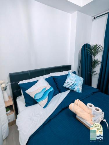 Bett mit blauer und weißer Bettwäsche und Kissen in der Unterkunft Azure Blue Cozy Unit with PS4 & Netflix in Manila