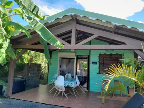 een groen huis met een pergola op een terras bij Chez Mélanie in Sainte-Rose