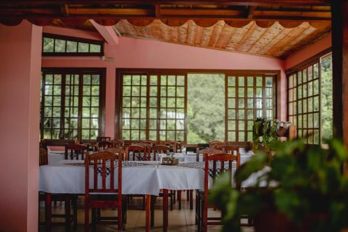 a dining room with tables and chairs and windows at Pousada Bugio da Serra in Novo Horizonte