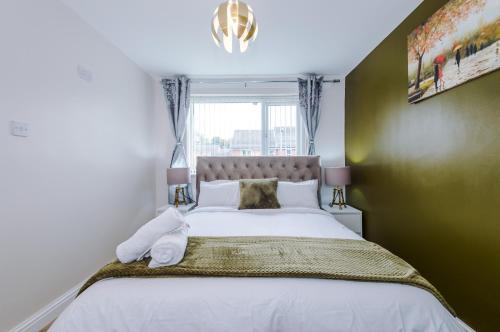 a bedroom with a large white bed with a window at Stylish 3 Bedroom home close to Manchester City centre in Oldham