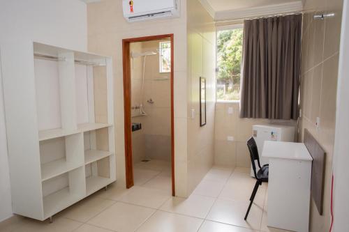 a bathroom with a toilet and a sink and a desk at Ribeiro Suit's Hotel in Araxá