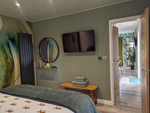 Gosling Lodge في دورهام: غرفة نوم بسرير وتلفزيون على الحائط