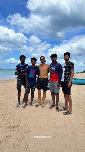 a group of men standing on the beach at 108 Palms Beach Resort in Trincomalee