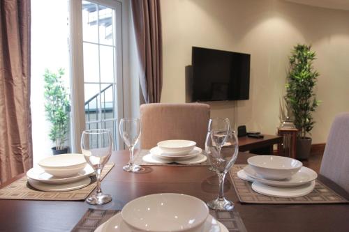 a dining room table with plates and wine glasses at Paddington Patio Apartment in London