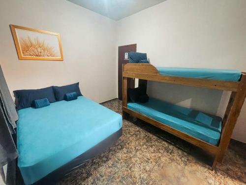 two bunk beds in a room with blue sheets at Pousada Califor in Nova Iguaçu