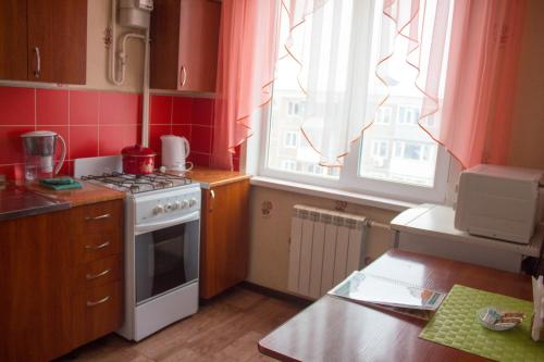 uma pequena cozinha com um fogão e uma janela em Сити em Petropavl