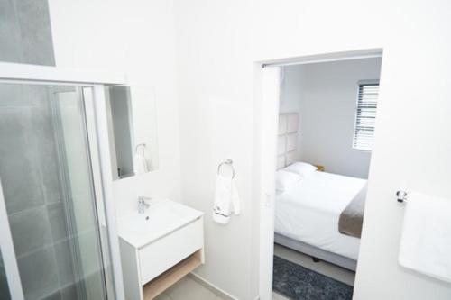 a bathroom with a shower and a sink and a bed at Stylish Apartment in Fourways in Sandton