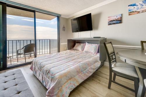 a bedroom with a bed and a table and a balcony at Pool Access 8th-Floor Condo on North Myrtle Beach in Myrtle Beach