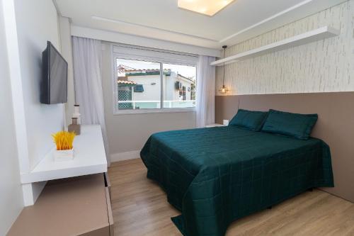 a bedroom with a green bed and a window at Varandas do Atlântico 101A - Excelente apartamento em condomínio de luxo a beira mar - Piscina climatizada - Academia - (Consultar serviços de roupas de cama e banho) in Bombinhas