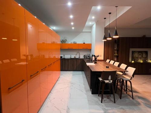 une cuisine avec des armoires orange et une table en bois dans l'établissement Magnifique maison contemporaine proche lac d’Aix, à Aix-les-Bains