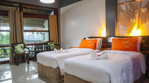 two beds in a room with orange and white pillows at Daluyong Beach Resort in General Luna