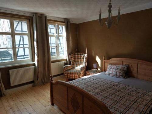 a bedroom with a bed and a chair and windows at Fewo Dornröschen in Schieder-Schwalenberg