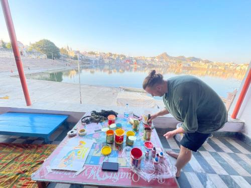 un hombre de pie junto a una mesa con bebidas encima en Doctor Alone, en Pushkar