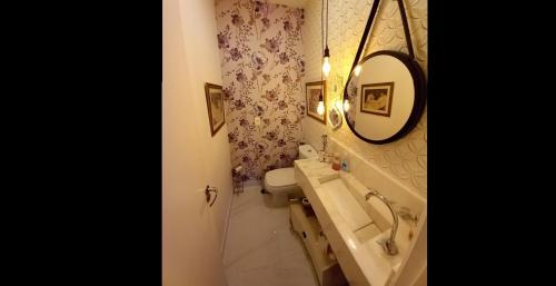 a bathroom with a sink and a toilet and a mirror at Apartamento Le Quartier - no centro, dois quartos, wi-fi, garagem, piscina, ar-condicionado, jacuzzi, sauna, etc in Juiz de Fora