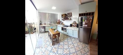 a kitchen with a refrigerator and a table in it at Apartamento Le Quartier - no centro, dois quartos, wi-fi, garagem, piscina, ar-condicionado, jacuzzi, sauna, etc in Juiz de Fora