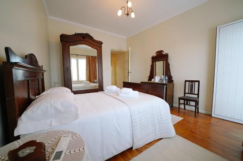 a bedroom with a large white bed and a mirror at Alijo Vintage House in Alijó