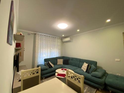 een woonkamer met een blauwe bank en een tafel bij Apartment Shkoder in Shkodër